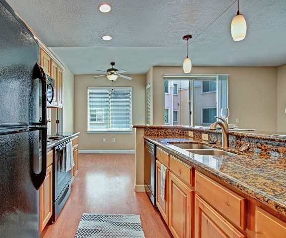 A kitchen with stainless steel appliances and wooden cabinets at Bridges Apartment Homes. 