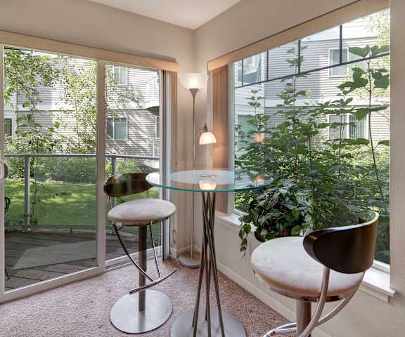 A dining area with a glass table and chairs and a balcony at Admirals Code Apartments