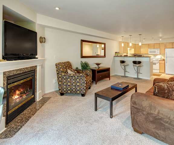 A living room with a fireplace and a couch at Admirals Cove Apartments. 