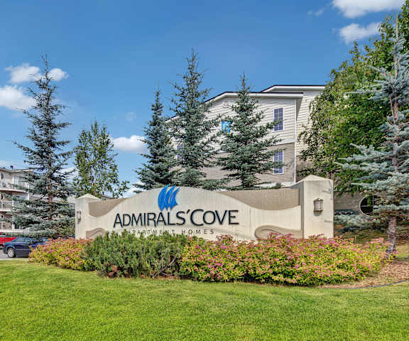 Sign in front of Admirals Code Apartments Homes with green space in front of it.