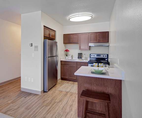 The kitchen with brown cabinets and white countertops at Century Plaza Apartments. 