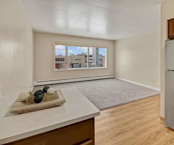 An empty living room and kitchen with a window at Century Plaza Apartments. 