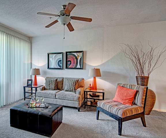 Living room with a couch, plush chair, lamps, and a coffee table at Acclaim.                                                                                                                                                                                                                                                                                                                                    