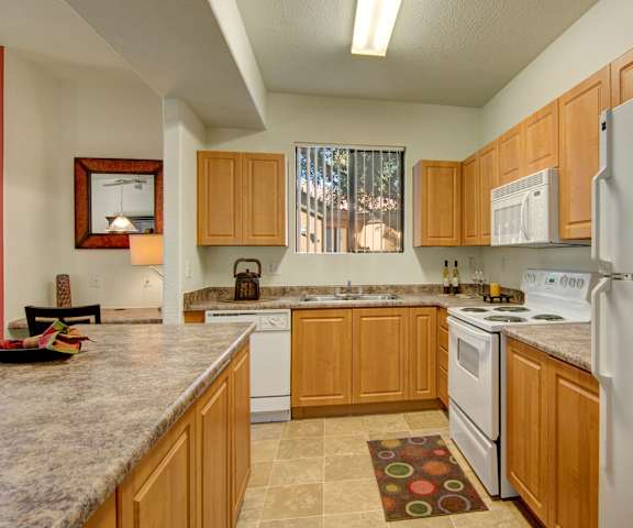 A kitchen with cabinets, white appliances, and granite countertops at Arezzo. 