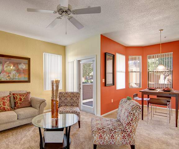 A living room with wide windows, a ceiling fan, and a couch at Arezzo. 