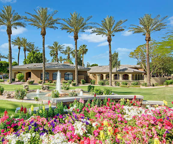The exterior lawn and fountain with the palm trees and the tan office building behind it at Reserve at Arrowhead Apartment Homes. 
