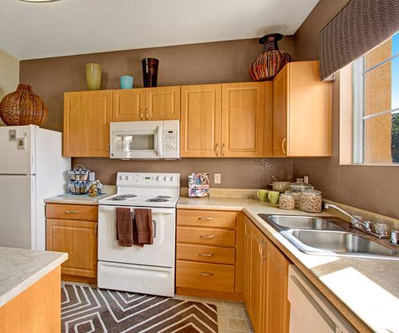 A kitchen with white appliances and wooden cabinets at Fresco. 