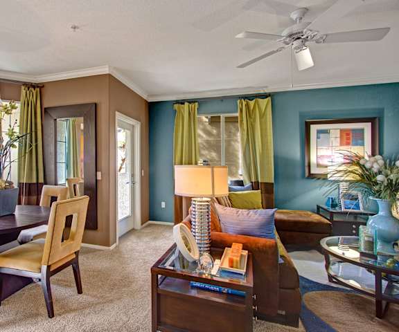 The resident lounge with a blue and tan walls, dining table and chairs, couches, plush chairs, decorations, and coffee tables at Fresco. 