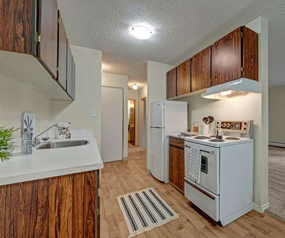 A kitchen with white appliances and counters at Cambridge West Apartment Homes. 