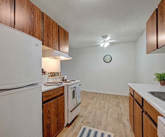 A kitchen with white appliances and counters at Cambridge West Apartments. 