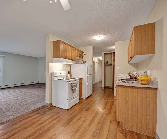 An empty living room with hardwood flooring and kitchen at Cambridge West Apartments. 
