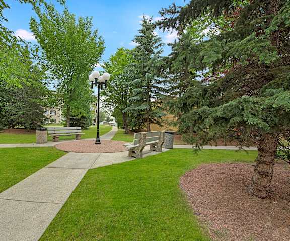 A park with benches and trees and a lamp post at Cambridge West Apartments. 