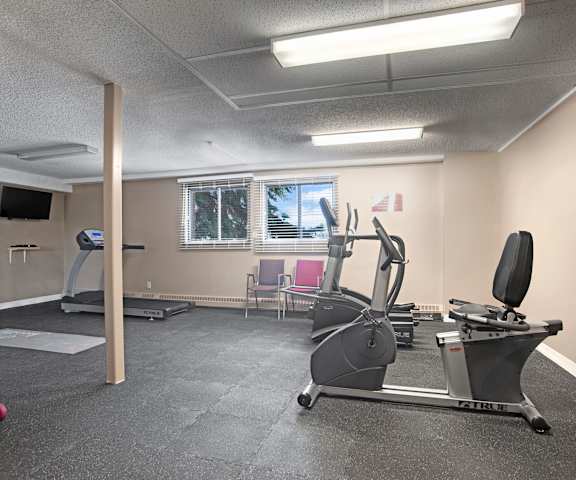 A gym with cardio machines, TVs, and weights at Edgemont Heights. 