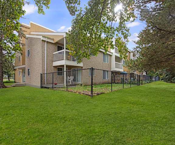 The outdoor view of the apartments, showing the fenced in yards for the apartments, each with a patio surrounded by trees at Gateway Gardens.