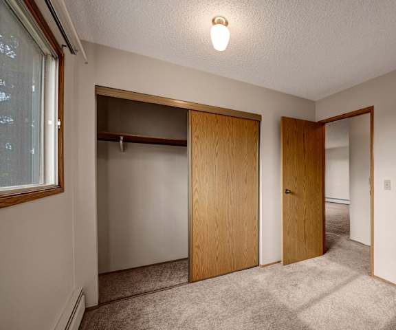 An empty bedroom with a closet and a window at Gateway Square. 