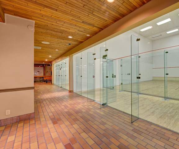 A brick hallway showing squash courts behind glass doors at Ranchlands Apartment Homes. 