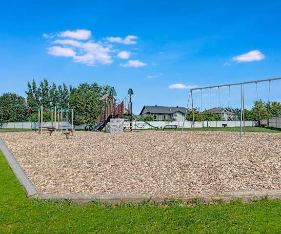 The fun playground with a slide and swing set for kids at Sol Terrace Apartment Homes. 