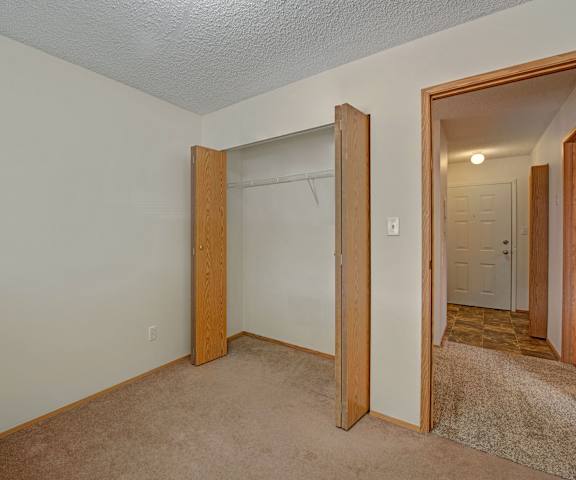 A large, empty carpeted bedroom with overhead lighting and a closet at Sol Terrace Apartment Homes.