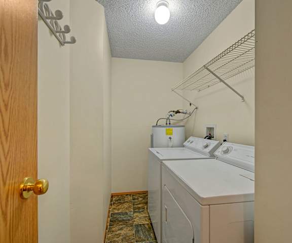 The laundry room with shelves, a washer, and a dryer at Sol Terrace Apartment Homes. 