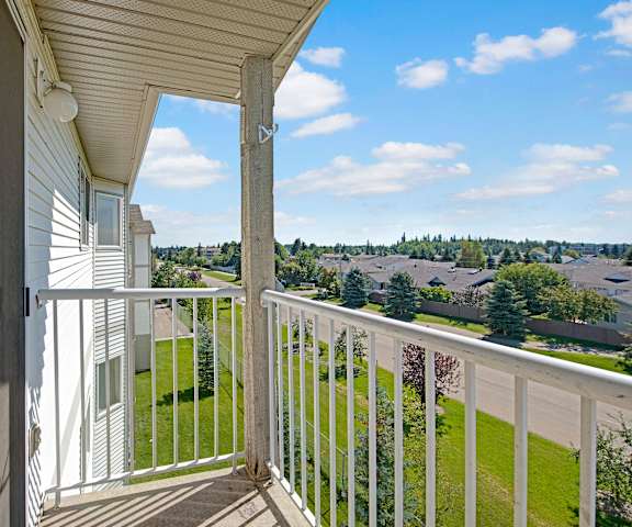 A beautiful white and gray balcony with a view of the grassy backyard and the surrounding residential area at Sonora Apartment Homes. 