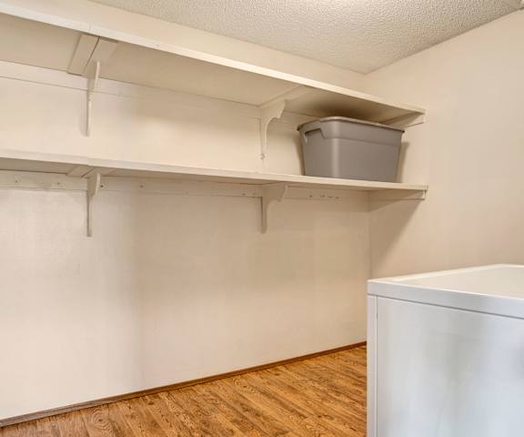 The laundry room with shelves, a storage bin, a washer, and a dryer at Ventana Apartment Homes. 