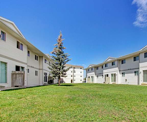 The beautiful exterior of the apartments and the green space with grass, trees, and shrubs at Westhaven Estates Apartment Homes. 