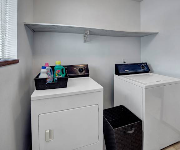 The laundry room with shelves, a washer, and a dryer at Willow View Apartment Homes. 
