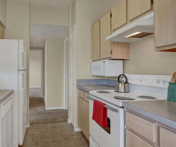 A kitchen with white appliances and tan counters at Camelback Pointe Apartments. 