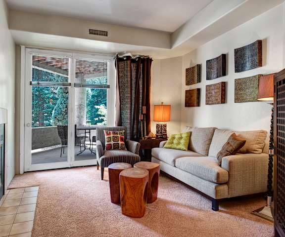 A living room with a couch and a fireplace and a balcony at Cheyenne Creek.