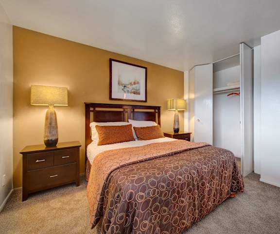 A bedroom with a queen-size bed, closet, and nightstands at Copper Stone Apartments. 
