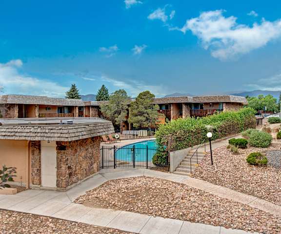 The outdoor pool with pool chairs, tables, and chairs and garden at Copper Stone. 