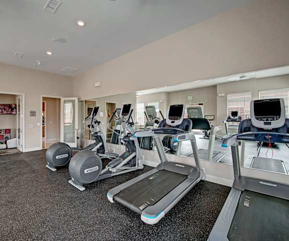 A gym with cardio machines, TVs, and weights at Elements at Briargate. 