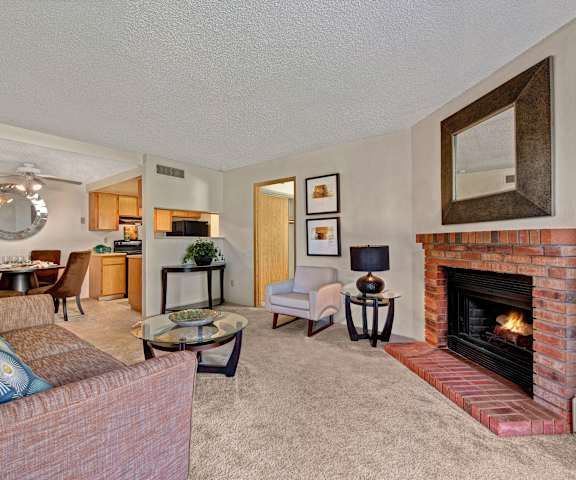 The living room with a couch, plush chairs, coffee table, decorations, a TV, and view of the dining room and the kitchen at Grand View. 