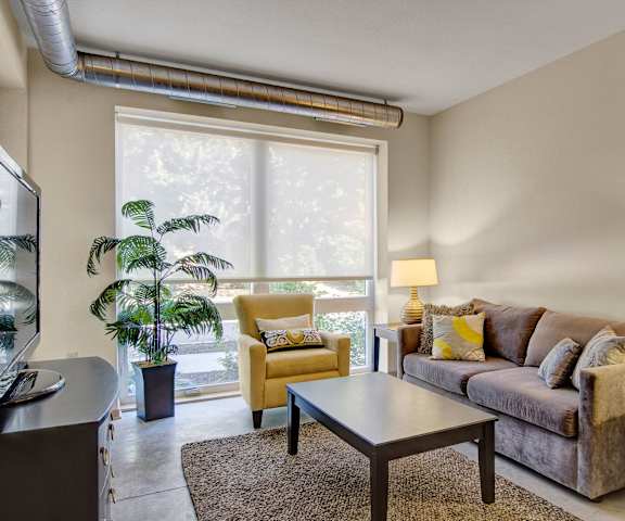 A living room with a couch and chairs and a large window at 7West. 