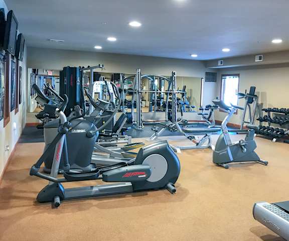 A gym with cardio machines, TVs, and weights at Grand River Estates. 