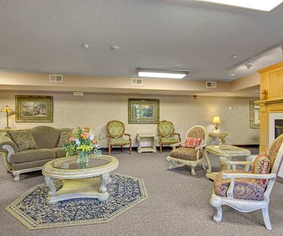 The resident lounge with a fireplace, couches, decorations, plush chairs, and coffee tables at Heritage Park. 