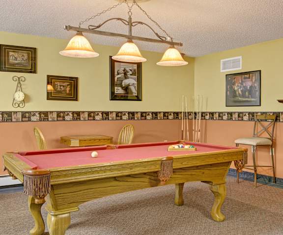 A resident lounge with tables, chairs, and a pool table at Heritage Park. 