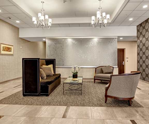The resident lounge with a fireplace, couch, decorations, TV, plush chairs, and coffee tables at Lofts at Farmers Market Apartments. 