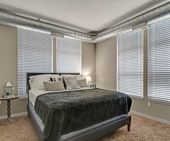 A bedroom with a queen-size bed, decorations, window, and nightstands at Marbella on Dean Apartments. 