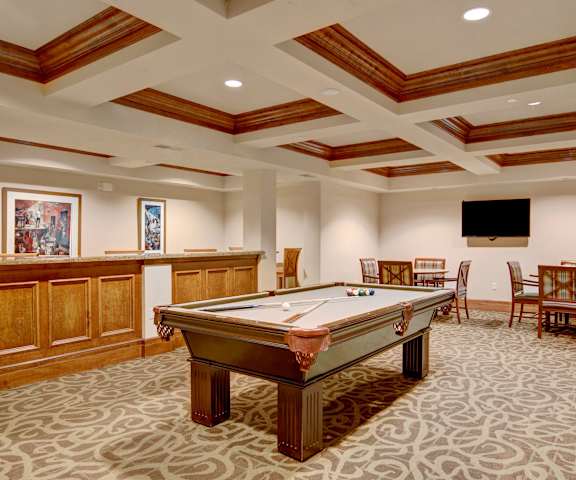 A wonderful resident lounge with tables, chairs, and a pool table at Stoneleigh at the Reserve Apartment Homes. 