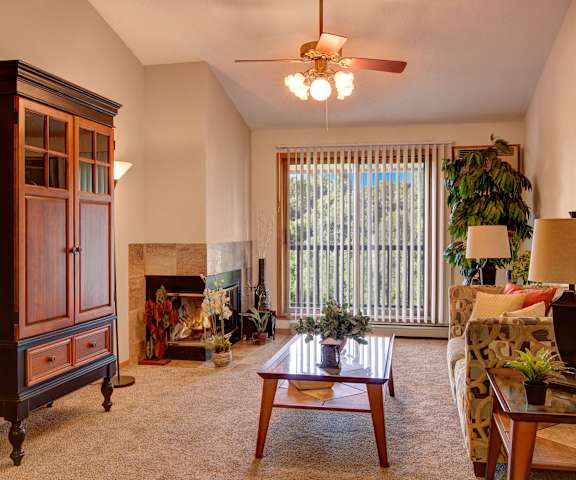 The spacious living room with a couch, throw pillows, large windows, a ceiling fan, wall art, plush chairs, coffee table, decorations, an entertainment system, large windows, a TV, and glass doors to the balcony at Town Centre Apartment Homes. 
