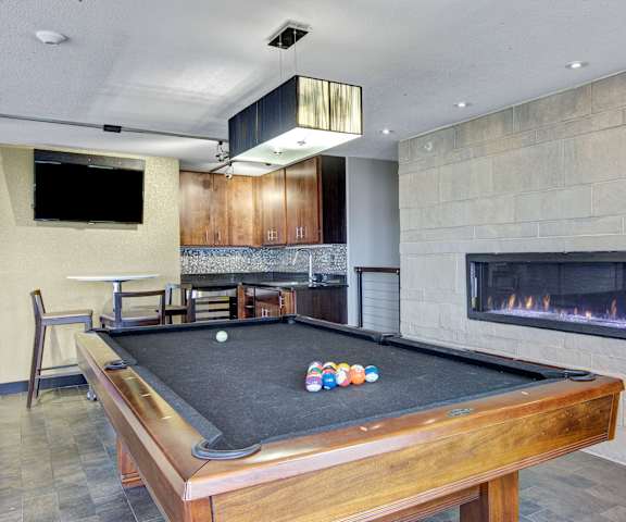A wonderful resident lounge with fireplace, kitchenette, TV, tables, chairs, and a pool table at Vue Apartment Homes. 