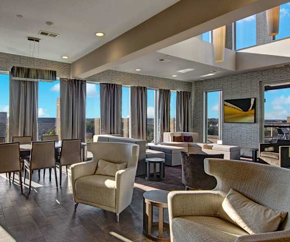 The amazing resident lounge with a fireplace, couches, decorations, large windows with curtains, dining room and chairs, plush chairs, and coffee tables at Vue Apartment Homes. 