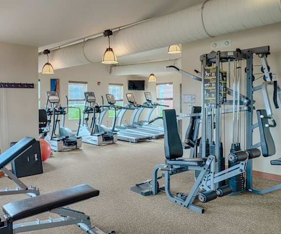 Fully equipped Fitness Center A gym with cardio machines, TVs, and windows at Dakota Ridge Apartments.