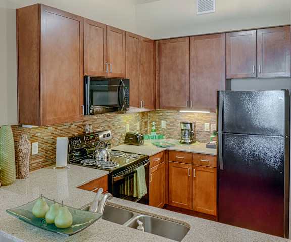 A kitchen with wooden cabinets and marble countertops at Dakota Ridge Apartments. 