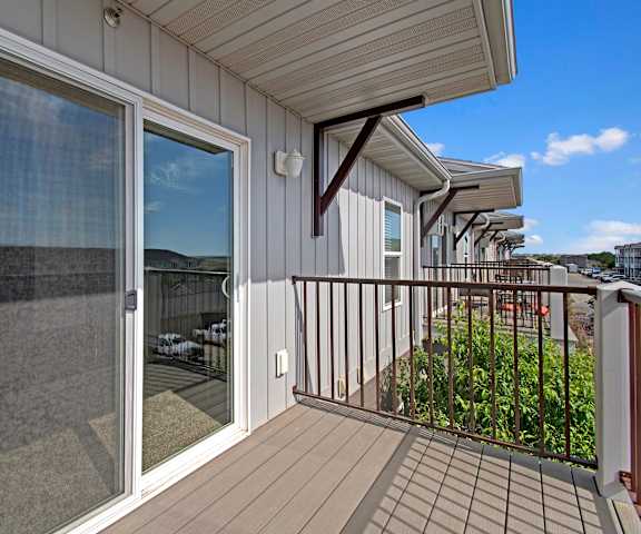 A row of outdoor balconies with sliding glass doors at Pheasant Ridge Apartments. 