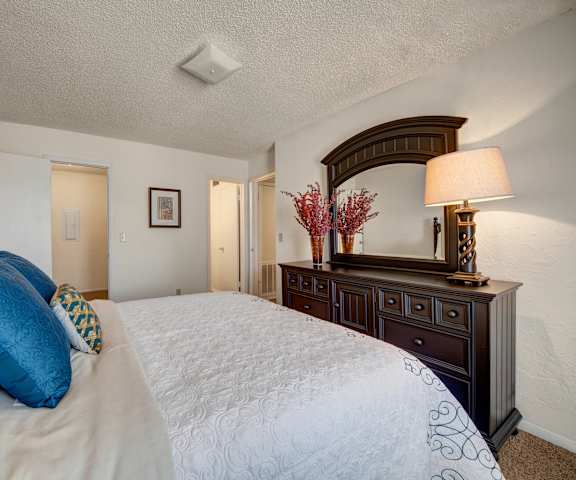 A bedroom with a queen-size bed, closet, and nightstand at Brookwood Village Apartments. 