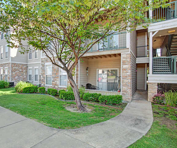 The pathway surrounded by grass and trees leading to the apartment building at Memorial Creek Apartments. 