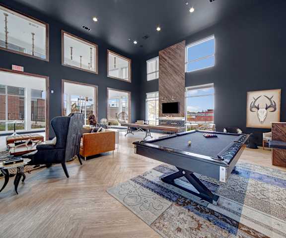 A resident lounge with tables, chess, wall art, windows and glass doors, chairs, and a pool table at Metropolitan Apartments. 
