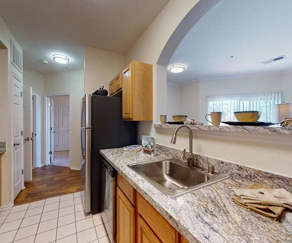 A cozy kitchen with stainless steel appliances, spacious marble countertops, and large wooden cabinets at Quail Landing Apartment Homes. 